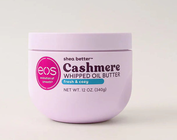 A 12 oz jar of EOS Cashmere Whipped Oil Butter in Pink & Blue, featuring a light lavender-purple container with a pink circular logo and black text, set against a clean, light off-white background.